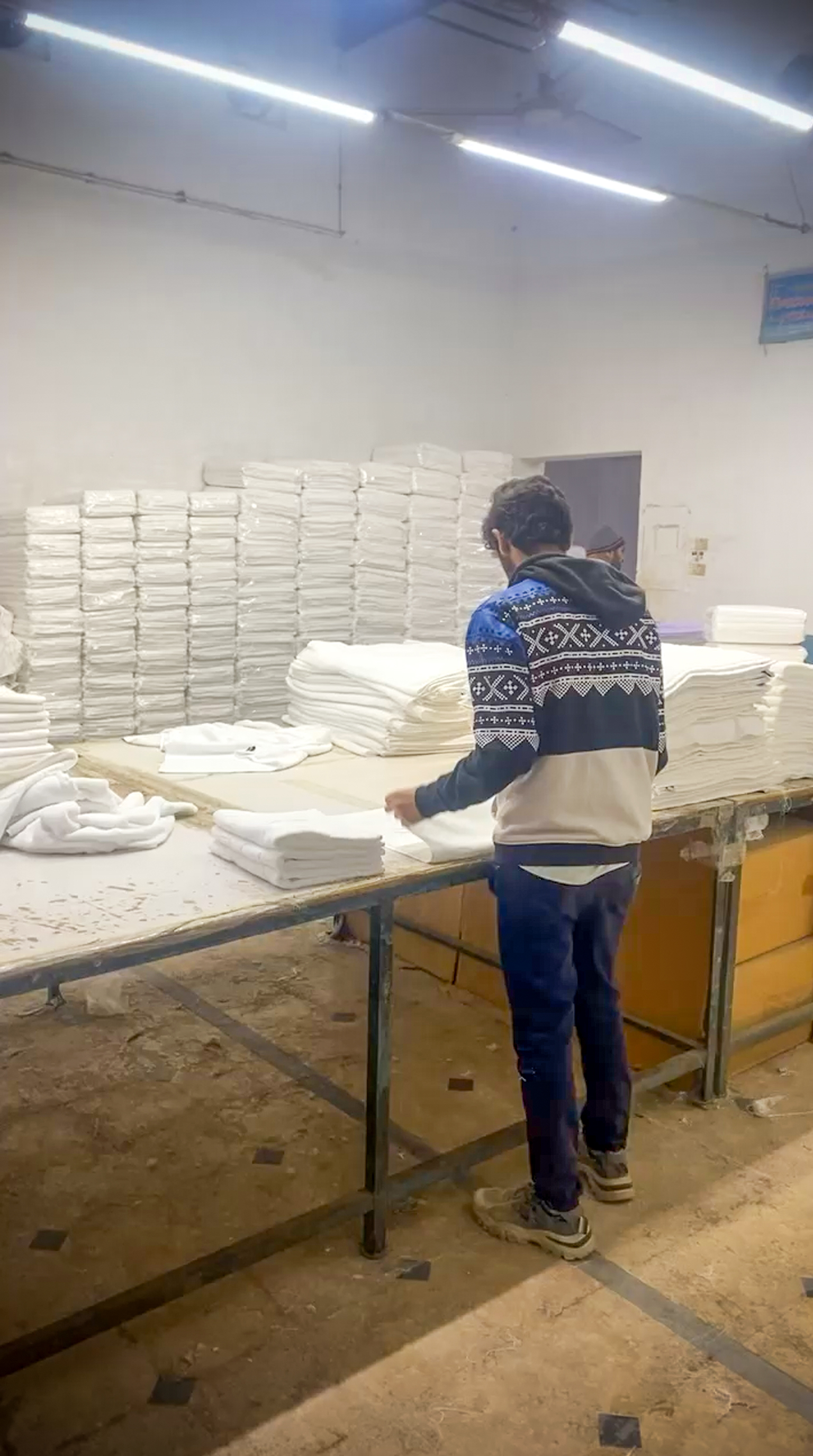 Geniluxe packing station showing worker folding and preparing linens for packaging